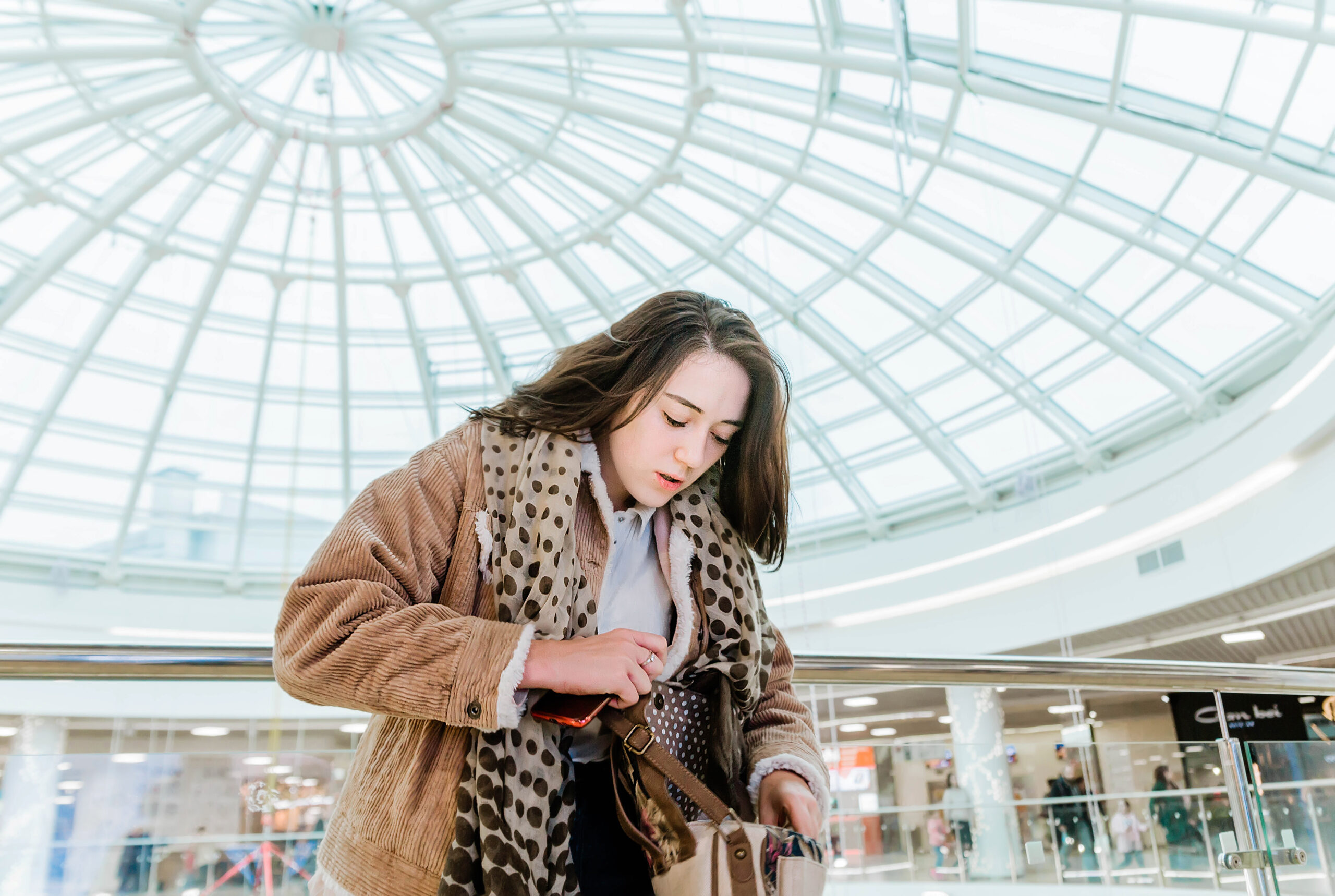 Photo of A girl in a shopping center looks in her bag and realizes that she was robbed or she forgot something.